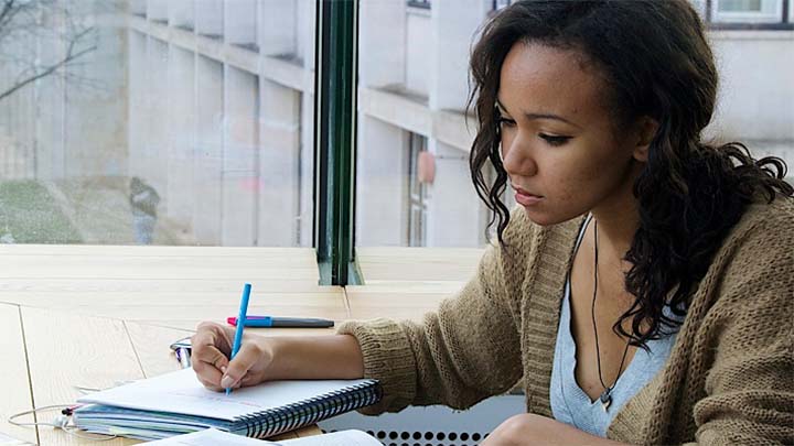 A student sat at a desk making notes.